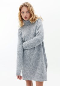 Abito maglione grigio chiaro, a coste, con collo alto, maniche lunghe e fessure laterali, realizzato in un materiale morbido e testurizzato.