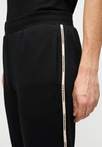 Μαύρο παντελόνι jogger με ελαστική μέση και πλαϊνή ρίγα με λευκή επωνυμία. Μαλακό ύφασμα με λεία υφή.