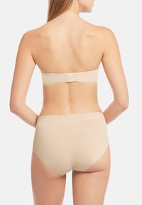 Nude strapless bra med bredt bånd og krok-lukking, sammen med høyt liv nude undertøy med glatt tekstur og minimale sømmer.