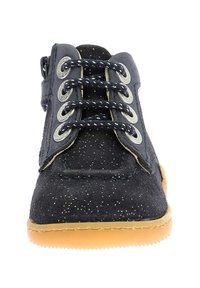 Botín azul de ante con destellos metálicos, ojales en dos tonos de gris, cordones en azul marino y suela de goma beige. Textura suave, diseño casual.