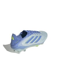 Crampon de football lilas clair avec une tige en synthétique, présentant trois rayures bleues, un design texturé et des crampons verts translucides.