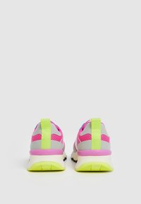 Rosa och grå sneakers med ovandel i mesh, gröna accenter och en framträdande hälflik. Har en tjock vit sula med svart mönster.