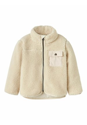 Giacca in pile color crema con zip anteriore completa e una singola tasca sul petto con bottone sul lato sinistro.