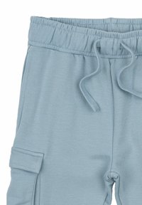 Ljusblå sweatpants med elastisk midja och dragsko, med sidofickor och ett mjukt, texturerat tyg.