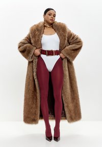 Brun kunstpelsfrakke, hvid bodysuit, burgunder strømpebukser og højhælede sko. Har et bredt rødt bælte med en guld spænde.