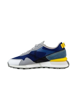 Zapatilla deportiva con parte superior de malla gris con acentos en azul marino y verde azulado, puntera blanca y una pestaña en el talón amarilla. Suela de goma texturizada para mayor agarre.