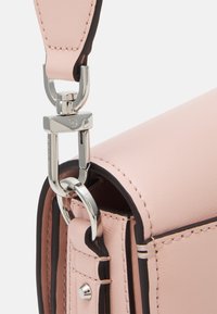 Angolo di borsa in pelle rosa chiaro con bordi scuri a contrasto, hardware argentato e dettagli di cucitura, dotata di chiusura e attacco per la tracolla.