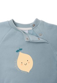 Hellblaues Sweatshirt mit rundem Halsausschnitt, das ein gelbes Zitronenmotiv mit einem lächelnden Gesicht und grünen Blättern zeigt. Druckknopfverschluss am Hals.
