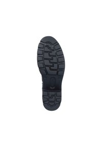 Black rubber shoe sole with textured tread pattern. Features deep grooves and circular sections for traction and stability.