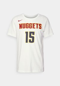 T-shirt en coton blanc avec "NUGGETS" en rouge et "15" en bleu à motif en maille, et un petit logo Nike rouge sur l'épaule gauche.