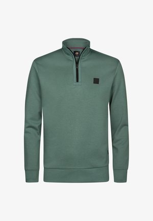 Jersey verde con cremallera de cuarto, cuello y puños acanalados. Presenta un pequeño parche de logo negro en el pecho. Hecho de una tela lisa.