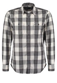 Camicia a maniche lunghe a quadri in bianco e nero, con due tasche sul petto, chiusura con bottoni e colletto classico. Materiale in cotone morbido.