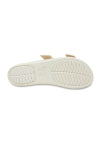 Cream-colored sandal sole with flexible rubber material, textured surface, zigzag tread pattern, two adjustable straps, and embossed logo detail.