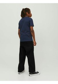 Marinblå bomull t-shirt med kort ärm, kombinerad med svarta vida jeans och svarta sneakers med vita detaljer.