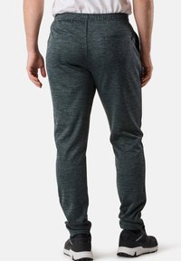 Gray athletic joggers made of textured fabric with a fitted design, featuring a zippered back pocket and elastic waistband.