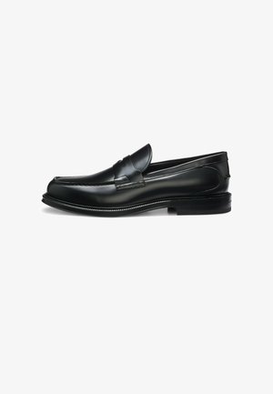 Schwarzer Leder-Pennyloafer mit niedrigem Absatz, Ziernähte und glatter polierter Oberfläche, von der Seite auf weißem Hintergrund gezeigt.