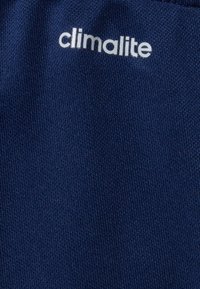 Námořnická modrá tkanina s texturovaným úpletem, s bílým textem "climalite". Materiál je lehký, vhodný pro aktivní sporty.