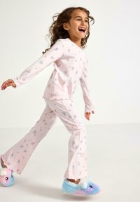 Set di pigiama rosa per bambini con motivo floreale; maglietta a maniche lunghe e pantaloni a zampa d'elefante; bordi sfrangiati. Abbinato a pantofole colorate e soffici.