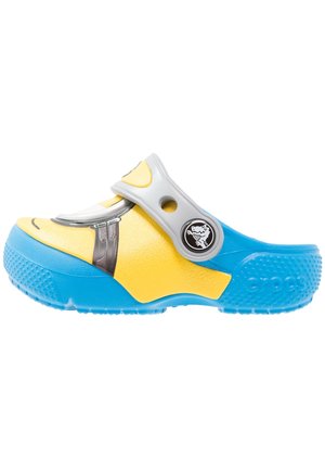 Zoccolo giallo e blu con cinturino grigio, apertura rotonda, suola testurizzata ed emblema di un personaggio sul lato.