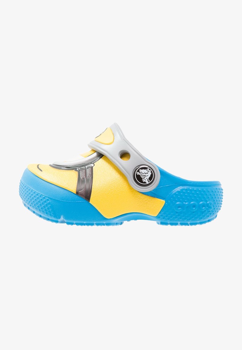 Sabot jaune et bleu avec une bride grise, une ouverture ronde, une semelle texturée et un emblème de personnage sur le côté.