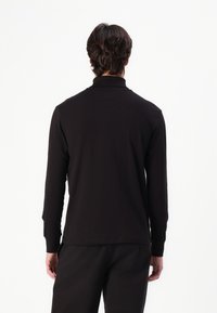 Black long-sleeve shirt with a high collar. Made of soft fabric with a smooth texture. Straight hem and fitted design with minimal accents.