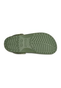 Groene rubberen Crocs-zool met een geprofileerd loopvlak, voorzien van ovale en rechthoekige vormen voor grip en stabiliteit, gelabeld met maat en merk.
