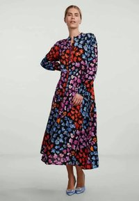 Robe midi florale à manches longues et boutonnière ; présente des fleurs rouges, bleues, roses et orange sur un fond noir ; silhouette fluide.