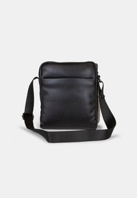 Borsa a tracolla in pelle nera con una texture liscia, fronte imbottito e tracolla in tessuto regolabile. Forma rettangolare con chiusura a zip.