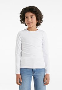 Weißes Langarmhemd aus weichem Stoff mit rundem Ausschnitt, getragen von einem Kind mit lockigem Haar, kombiniert mit blauen Jeans.
