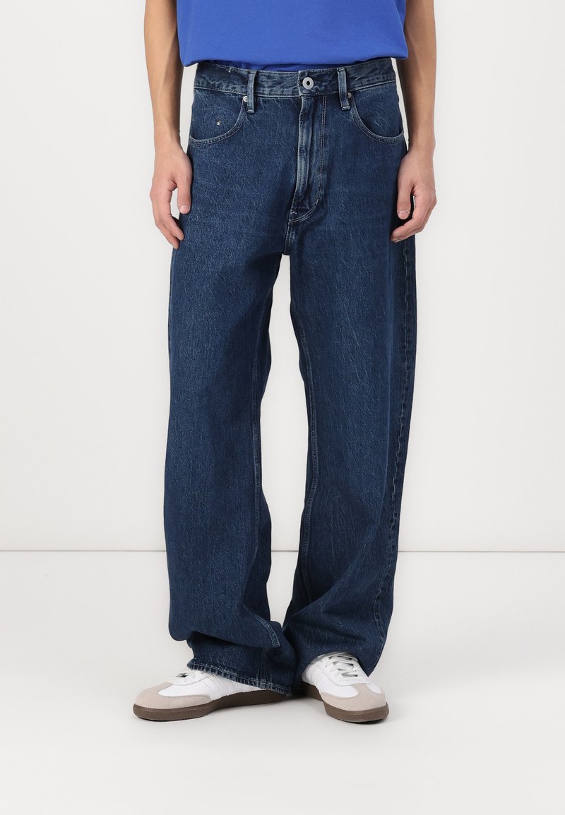 Mørkeblå vide denim-bukser med høj talje, fem lommer og en let falmet vask for tekstur.