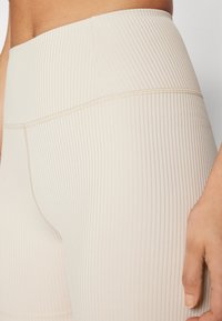 Beige ribbede leggings med høy midje, teksturert stoff og flate sømmer for komfort og fleksibilitet.