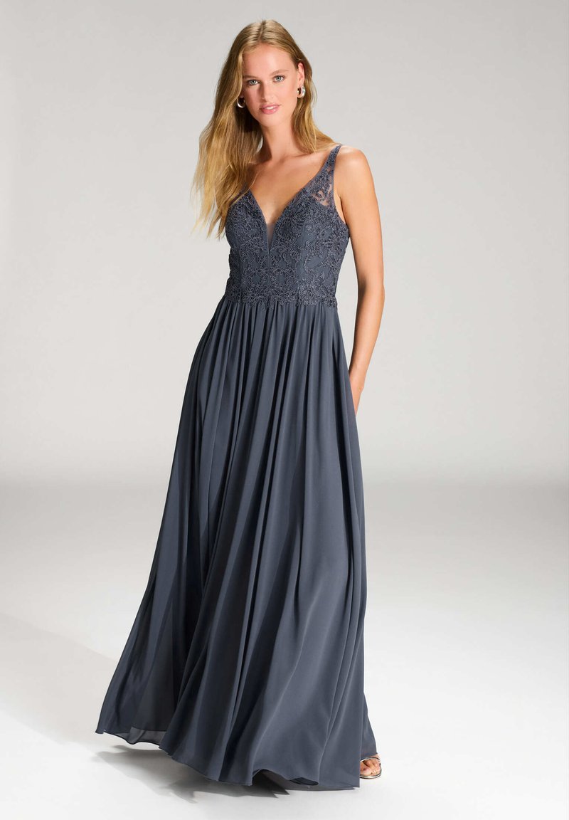 Langes Abendkleid in tiefem Marineblau, mit einem taillierten Spitzenoberteil mit V-Ausschnitt und fließendem Rock. Mit Taschen und dünnen Trägern.