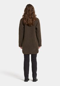 Brauner Fleece-Mantel mit strukturierter Oberfläche, langen Ärmeln und geradem Schnitt, getragen über schwarzen Hosen und Stiefeln, von hinten betrachtet.