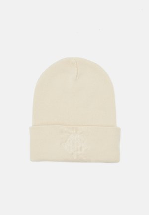 Krém színű kötött sapka hajtott szegéllyel és hímezett logóval az elején, lágy, texturált anyagból készült.