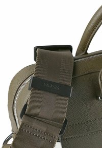 Groene leren tas met textuur en een afneembare bruine stoffen schouderband. Voorzien van zilverkleurige hardware en een ritsluiting. BOSS-logo op de band.