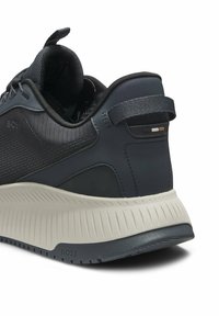 Dark navy sports shoe with a textured mesh upper and smooth accents. Features a thick, ridged sole in light gray and a pull tab at the heel.