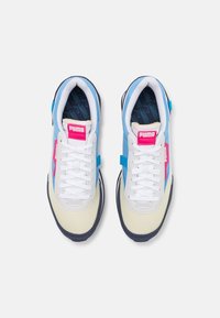 Les baskets Puma présentent un design en bleu clair, crème et marine, avec une tige texturée, des lacets blancs et un logo rose sur la languette.