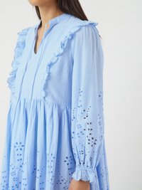Rochie de culoare albastru deschis, cu guler volanat, mâneci lungi și modele florale brodate. Prezintă o croială lejeră și un detaliu de talie strânsă.