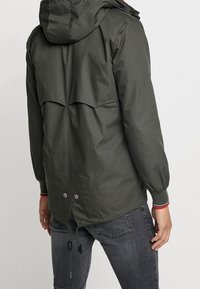 Groene jas met capuchon en een trekkoordzoom, met een gelaagd achterontwerp en elastische manchetten, gemaakt van gladde stof met een matte afwerking.