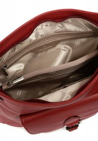 Interno di una borsa in pelle rossa con rivestimento beige, molteplici tasche con cerniera, texture liscia e dettagli del logo sul tessuto.