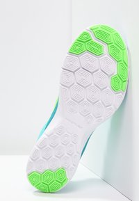 Sko sål med et hvidt, sekskantet mønster og grønne accenter. Materialet ser gummilignende ud med en tekstureret overflade. Overordnet kantet design.