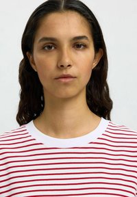 Red and white striped t-shirt with a round neck, featuring short sleeves and a soft cotton texture. Minimalistic design without embellishments.