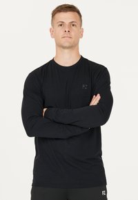 Svart långärmad skjorta i lätt tyg med en subtil textur och en liten "FZ"-logotyp på bröstet.