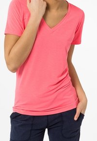 V-neck, short-sleeve t-shirt in bright pink, made of soft fabric. The shirt has a fitted silhouette and a smooth texture.
