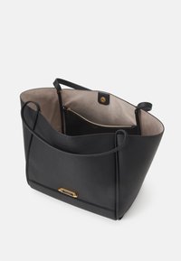 Black leather tote bag with a spacious interior, smooth texture, gold accents, and a zipper pocket, featuring long handles for carrying.