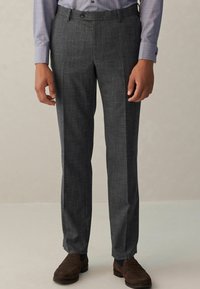 Graue maßgeschneiderte Hosen aus strukturiertem Stoff, mit flacher Vorderseite und schrägen Taschen, kombiniert mit braunen Slippers.