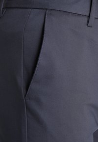 Navy blue trousers made from smooth fabric, featuring a flat front, side pockets, and clean seams for a tailored appearance.