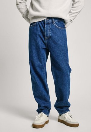 Blue denim jeans with a relaxed fit, featuring a classic five-pocket design and subtle fading. Paired with white sneakers.