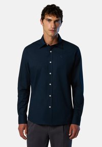 Camisa de manga larga azul marino con cuello puntiagudo, frente abotonado y botones plateados; presenta un pequeño logo en el lado izquierdo del pecho.