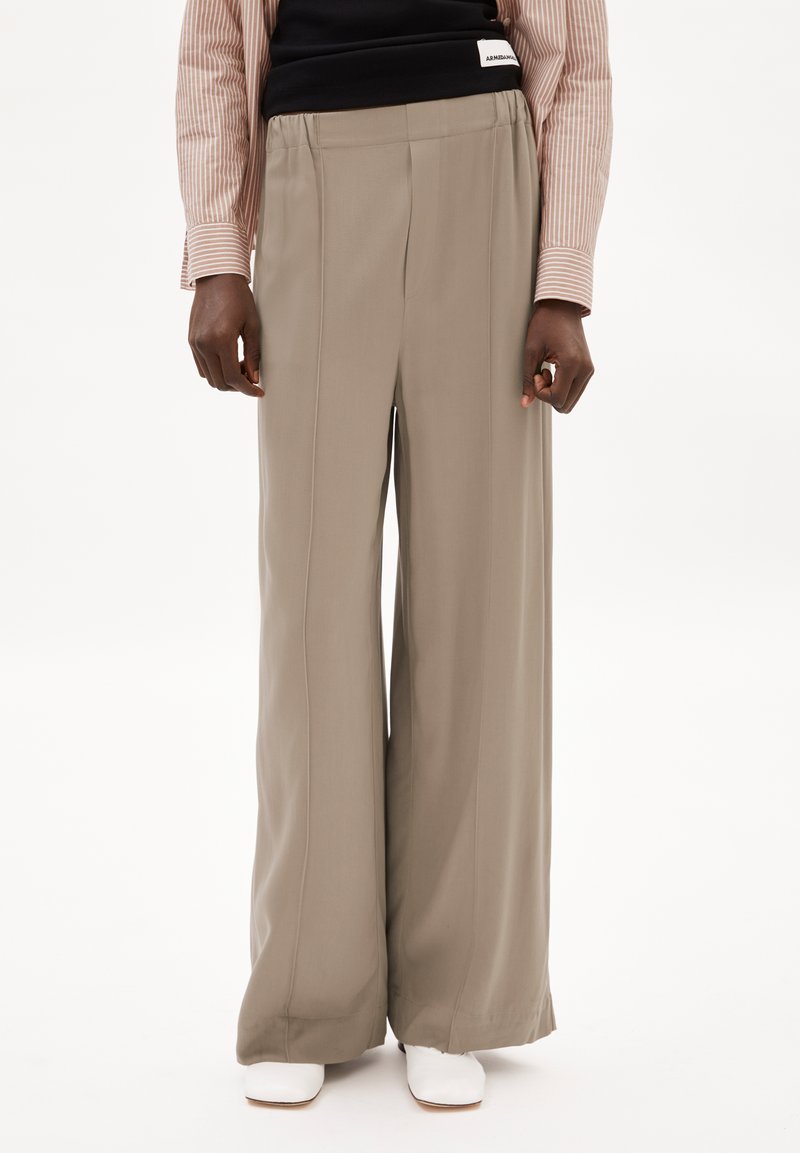 Pantalons larges en tissu taupe clair avec une texture lisse. Dotés de plis avant et d'une taille élastique.